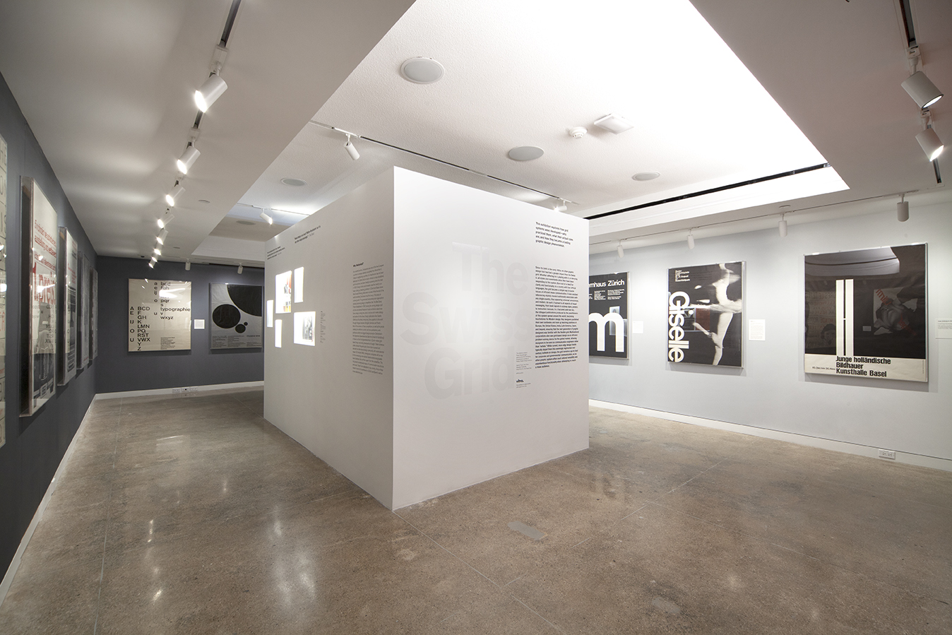 A photograph of the Swiss Grid gallery space with white and grey walls.