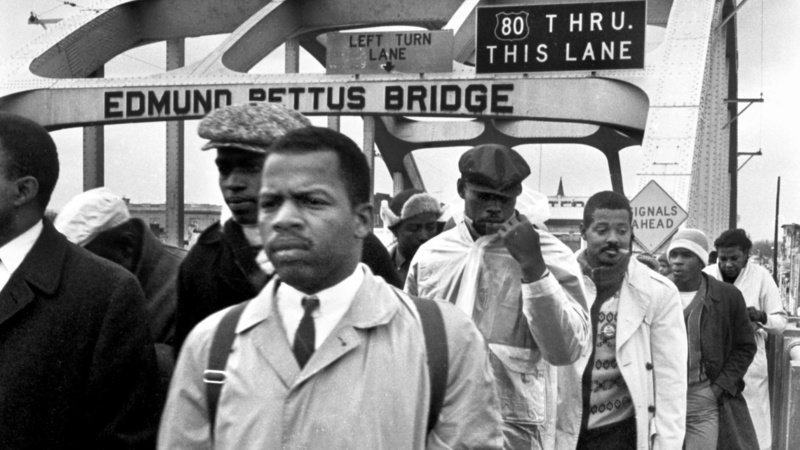 John Lewis—in his iconic coat—walks across the Edmund Pettus Bridge on the first attempted march to Montgomery, AL from Selma. Photo credit: Spider Martin/The Birmingham News